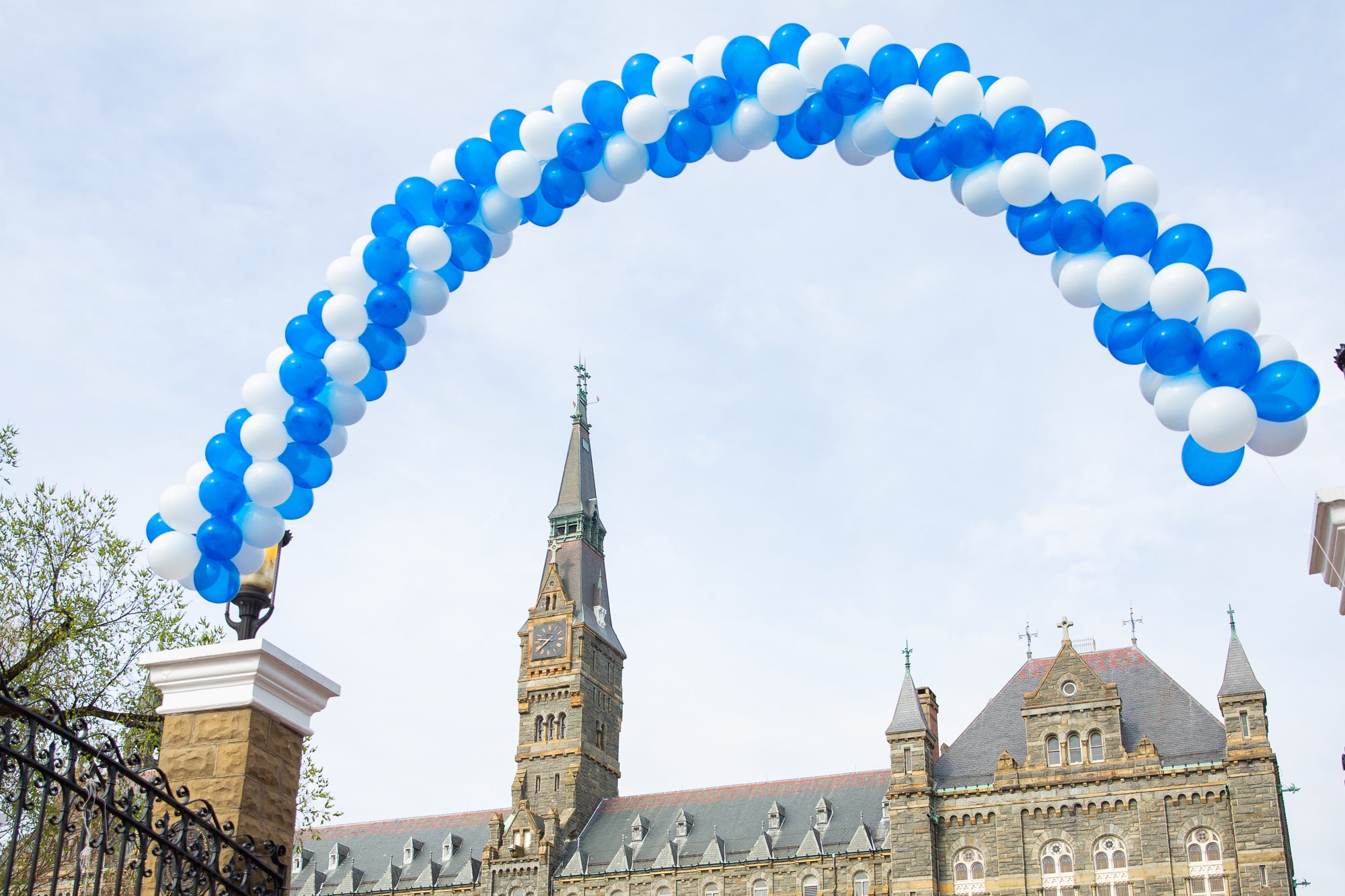 A white and blue balloon arch floats above the front gates on Georgetown's campus.