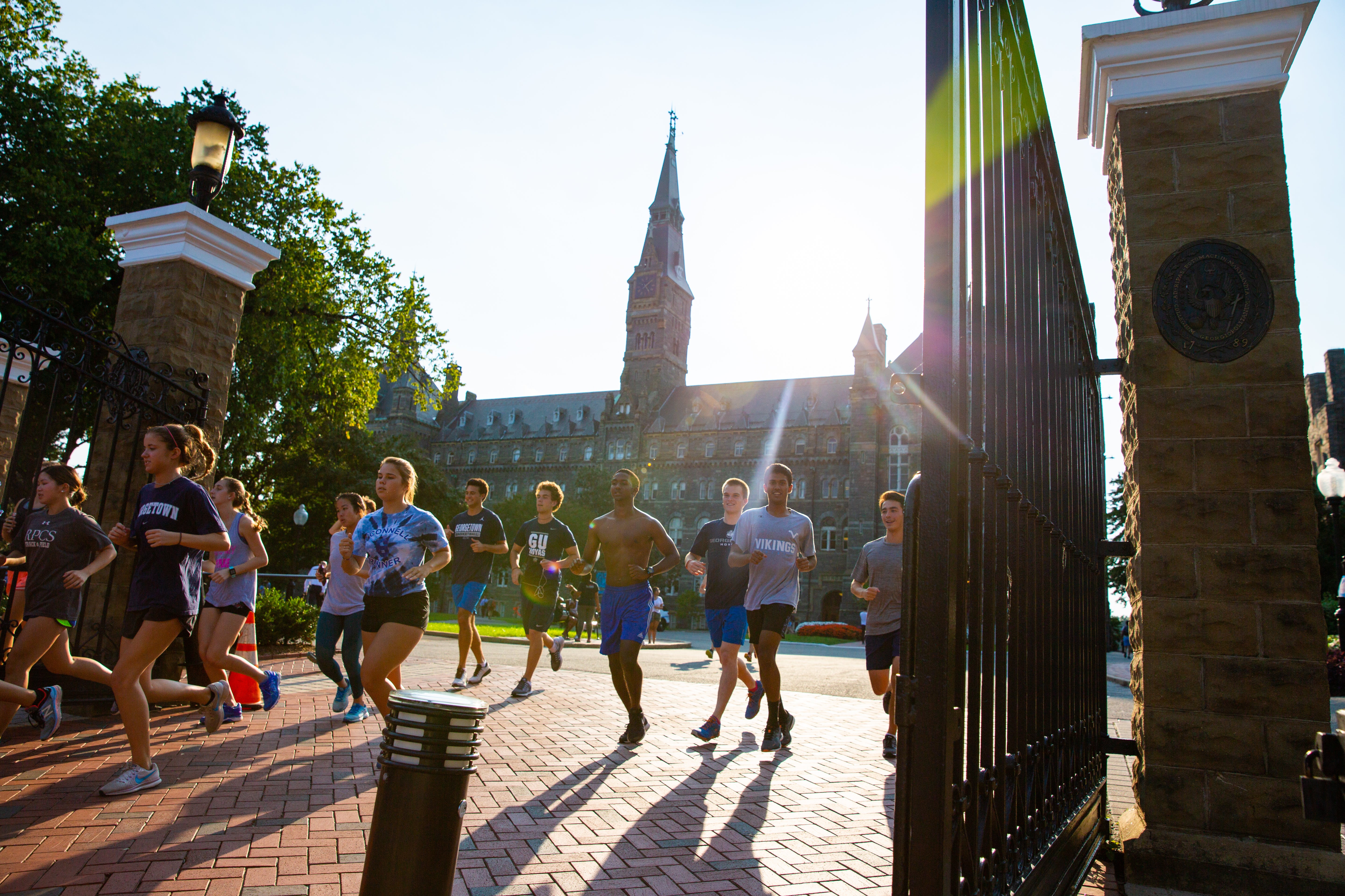 A group of runners running away from Georgetown's campus past the front gates.