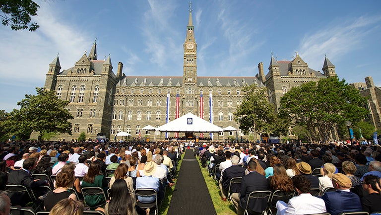 Crowds on the lawn outside of Healy Hall decorated for graduation ceremony.