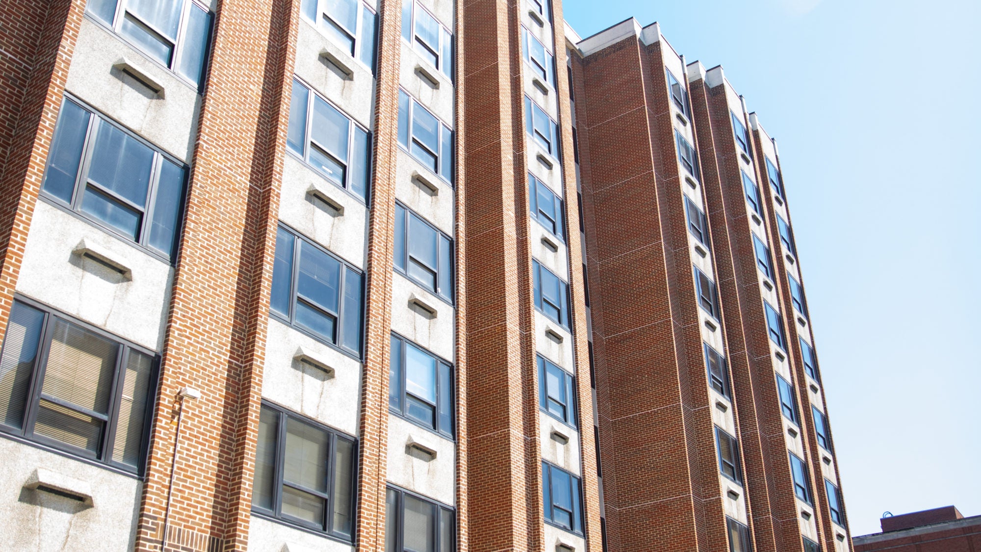 Students are shown walking past a tall campus dorm building.