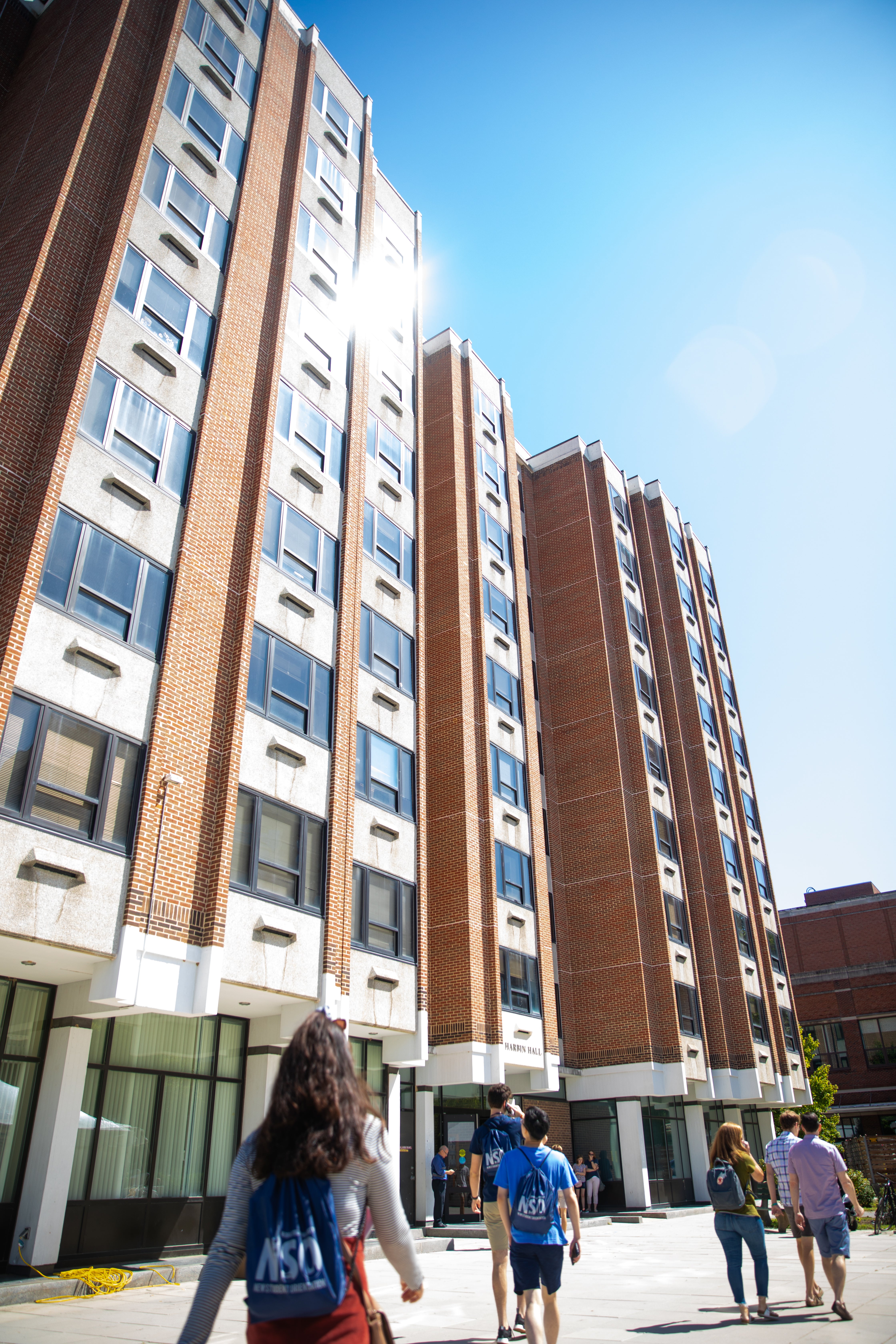 Students are shown walking past a tall campus dorm building.