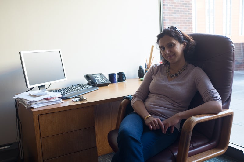 Professor Shareen Joshi smiles for the camera at her desk.