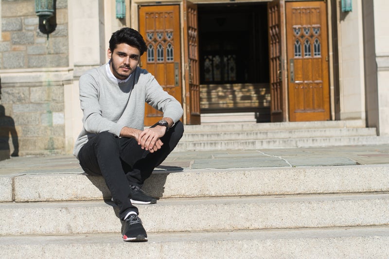 Zohaib Tahir smiles for the camera while sitting on steps.