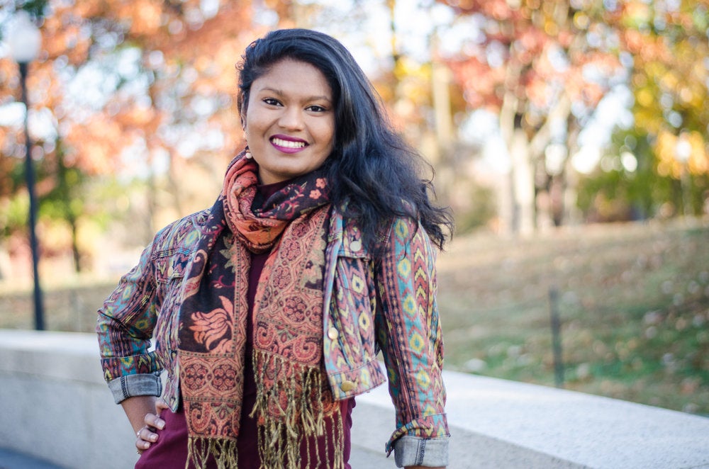 Neharika Khandavalli smiles for the camera in front of trees.