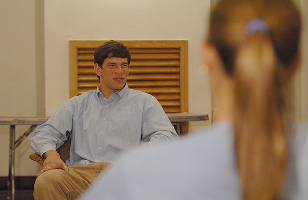 Dr. David C. Fajgenbaum sitting in a chair talking to a woman