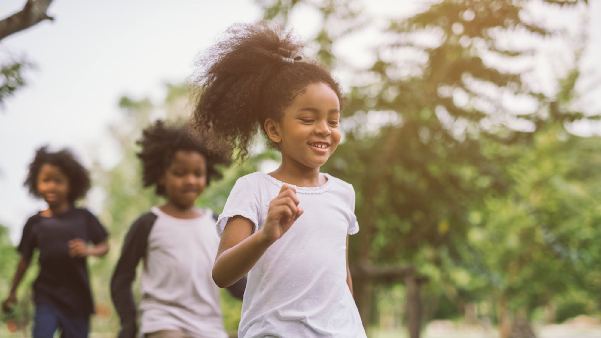 Three little girls run outside.