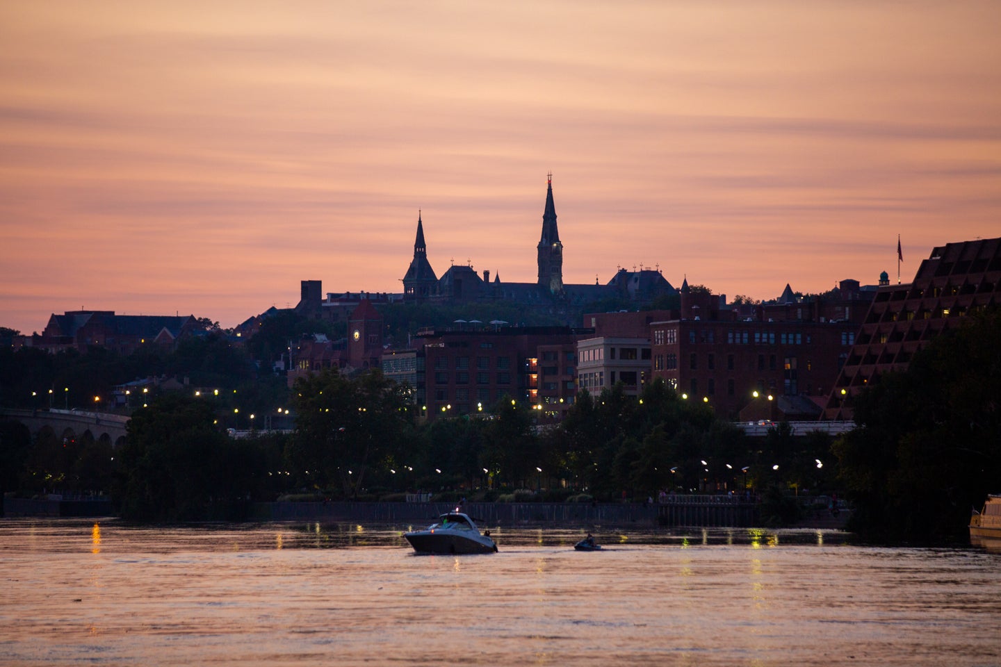 Photo displays the Georgetown waterfront, with the University backlit as a silhouette against a sunset.