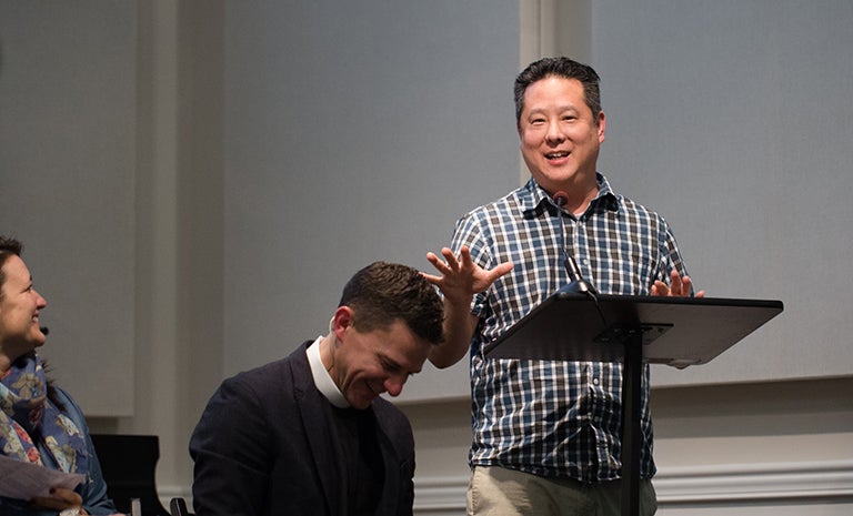 Steve Park at a podium with two people sitting and laughing.