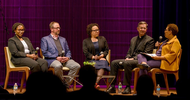 Panelists sit on a stage