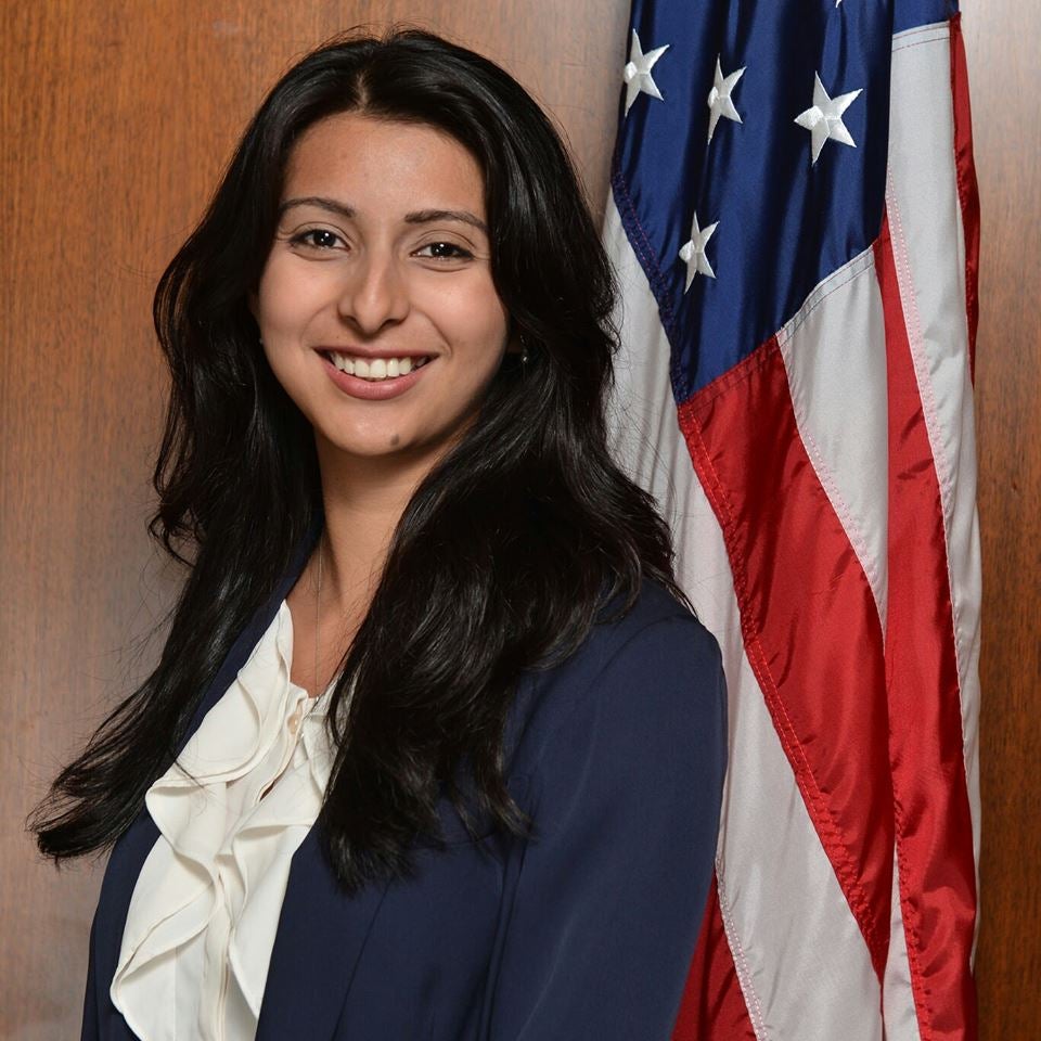 Donna Hernandez smiles for the camera in front of an American flag.