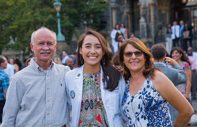 Hailey Roumimper in the center with her parents standing on either side of her smiling.