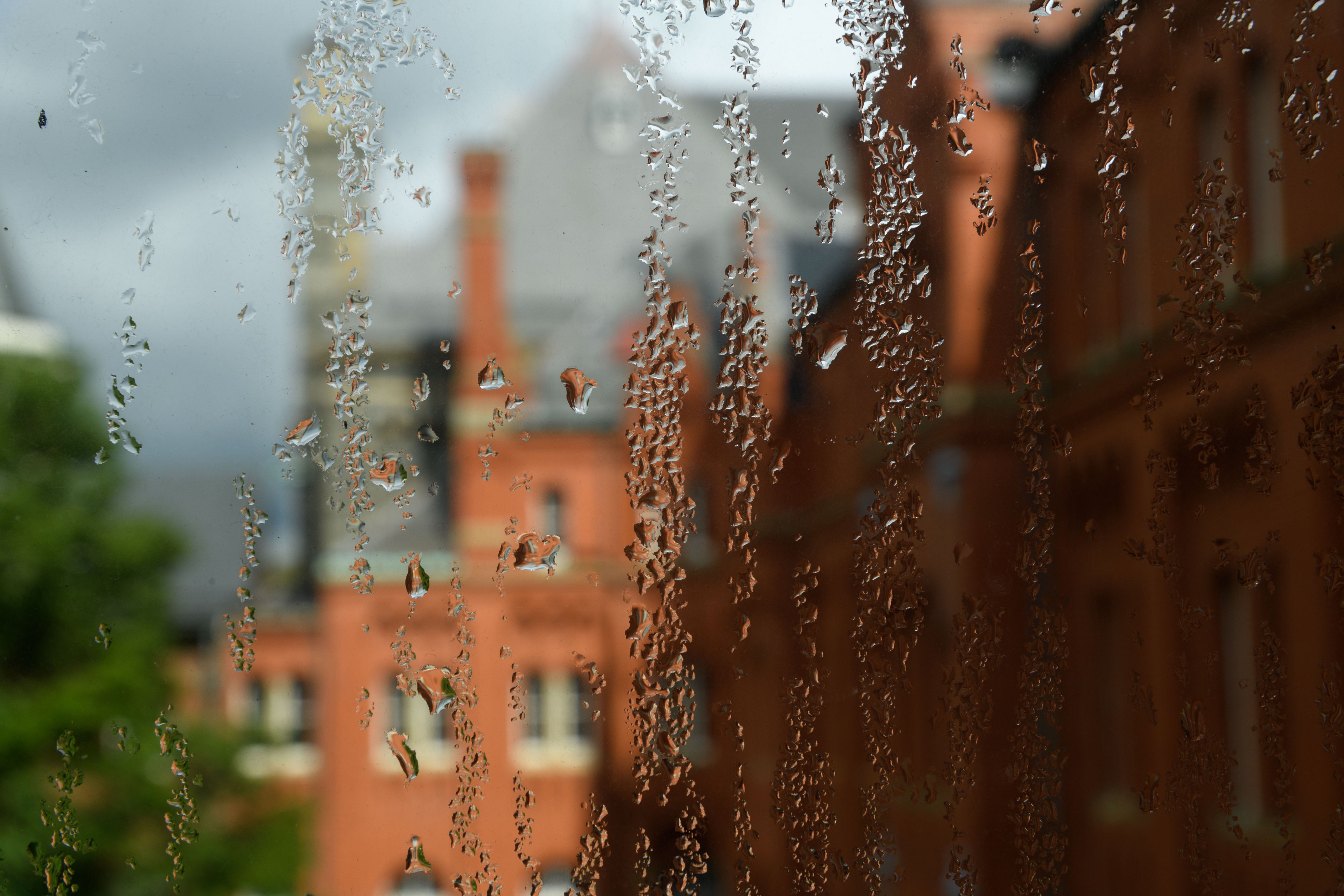 Rain trickles down a window with campus in the background