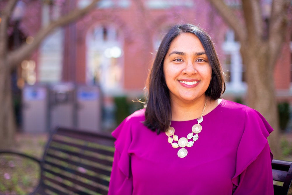 Devita Bishundat smiles for the camera while sitting on a bench.