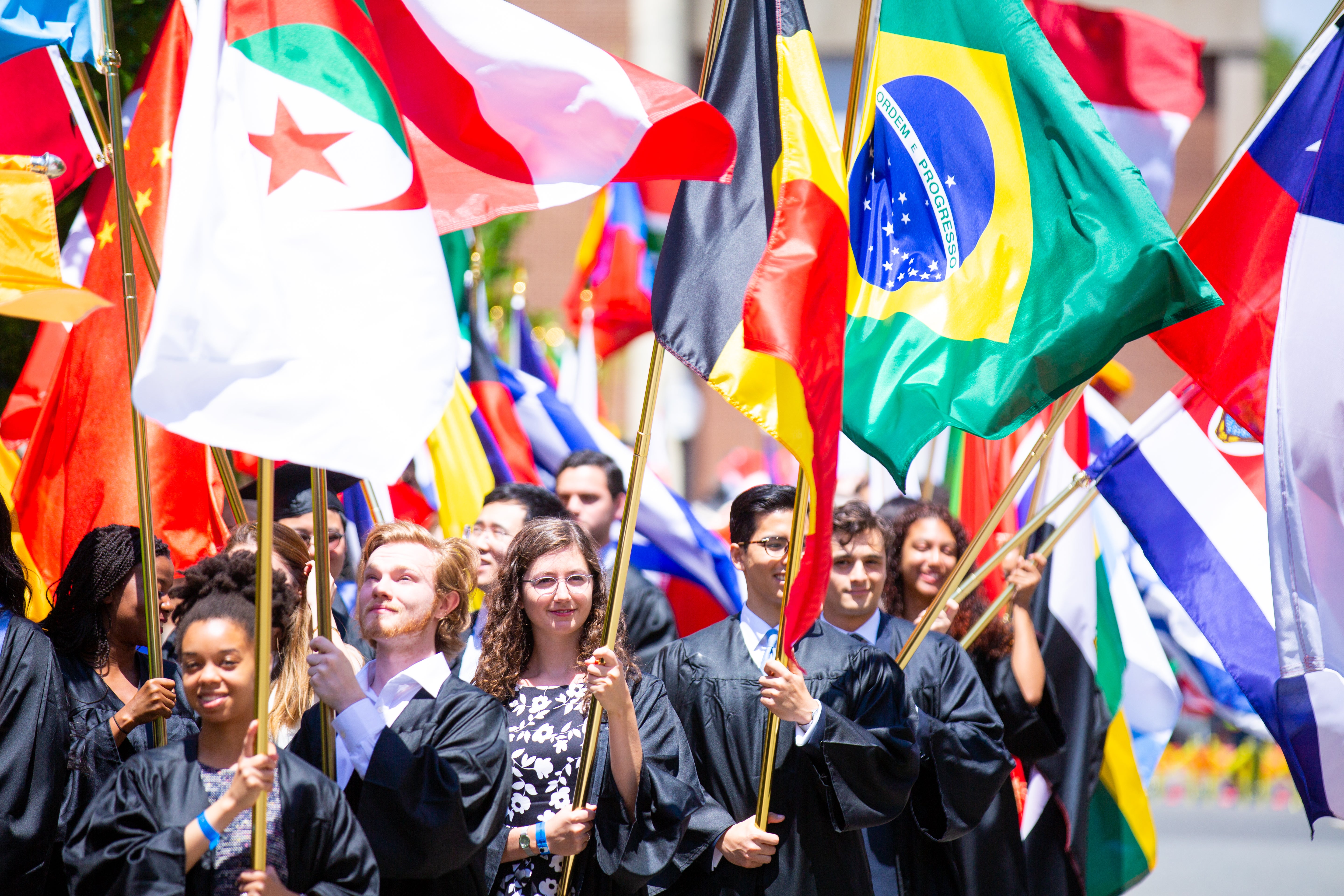 Georgetown students in caps and gowns holding large flags from different countries