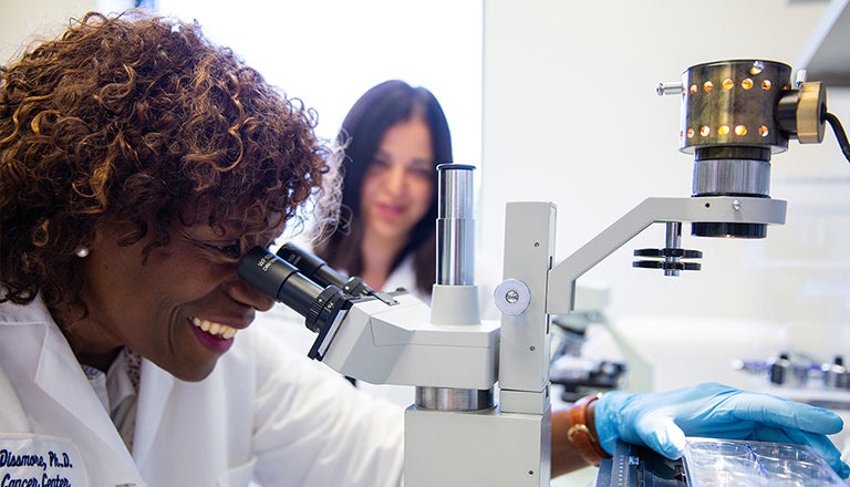 Two women looking into a microscope.