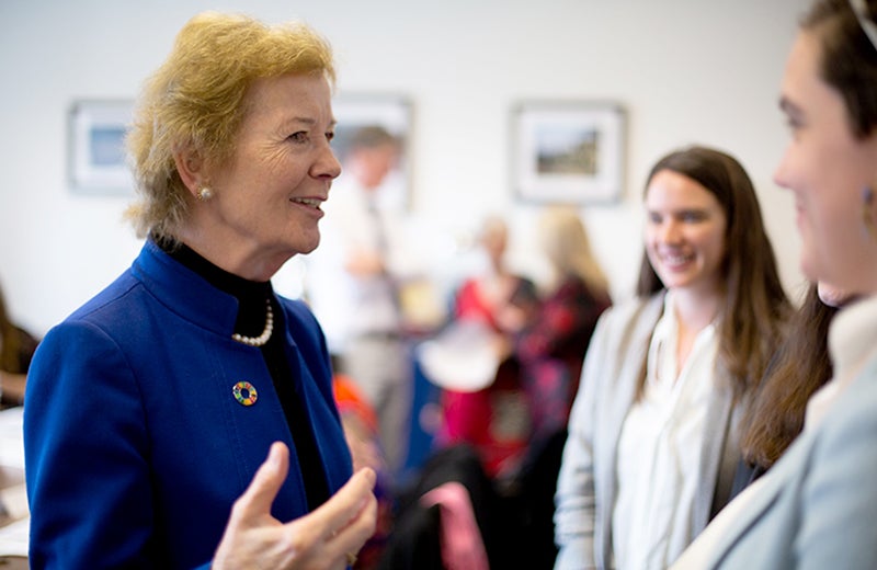 Former Ireland President Mary Robinson stands and talks with a few students with more students in the background