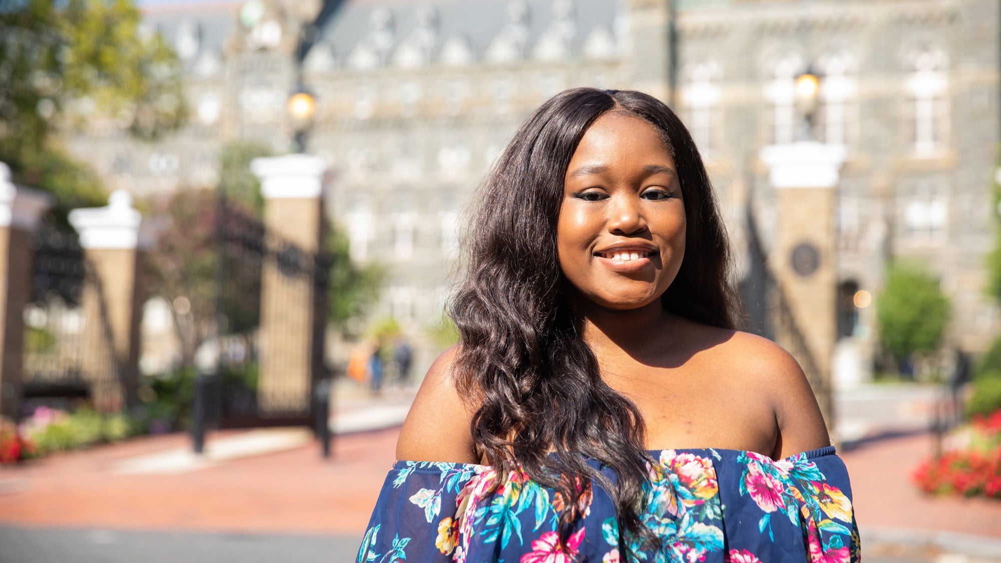 Omoyele Okunola stands outside with Healy Hall in the background.