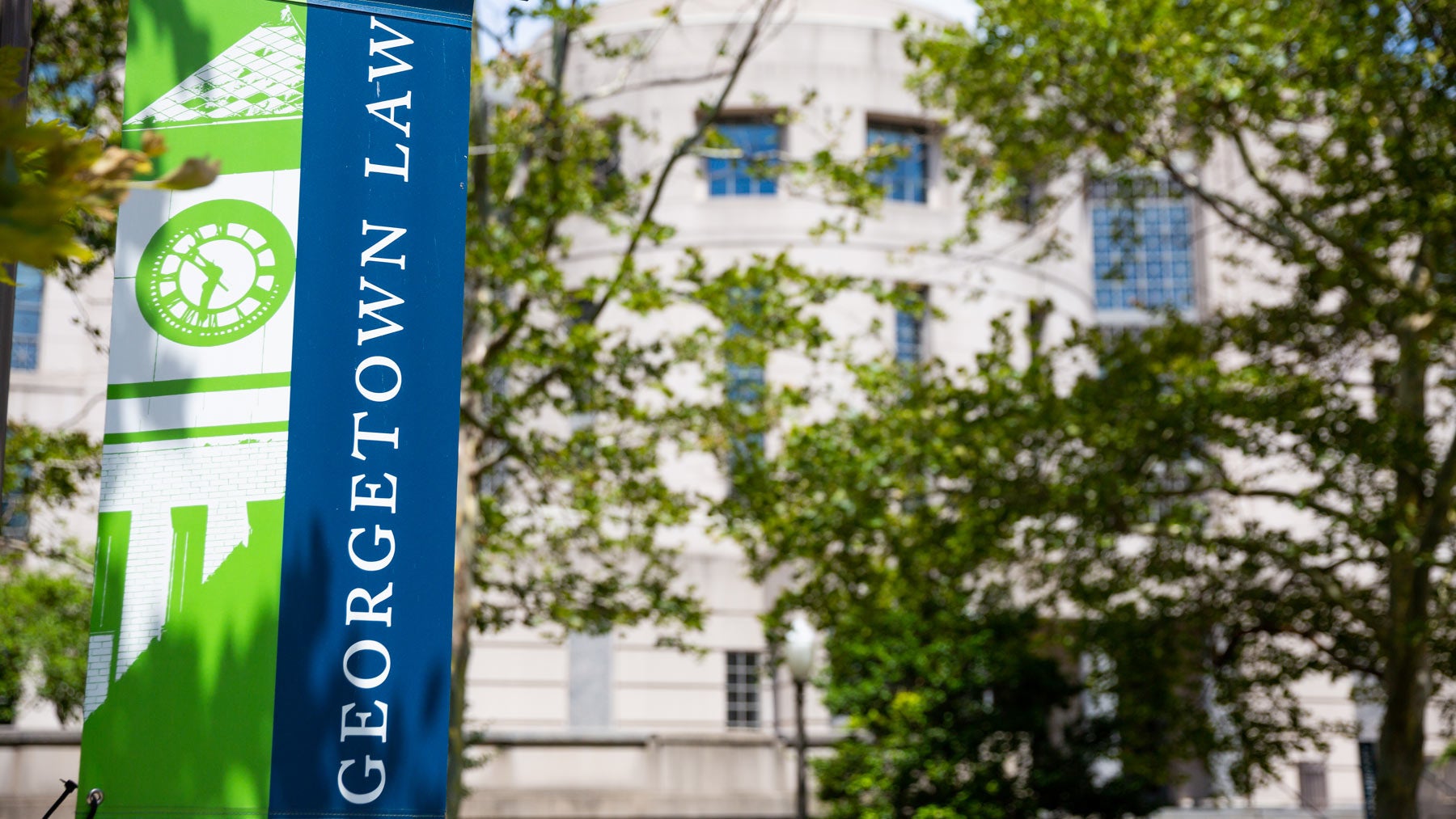 Georgetown Law banner nhangs in front of a building on campus.