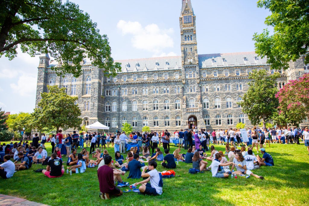 Students sit on the lawn in front of Healy Hall.