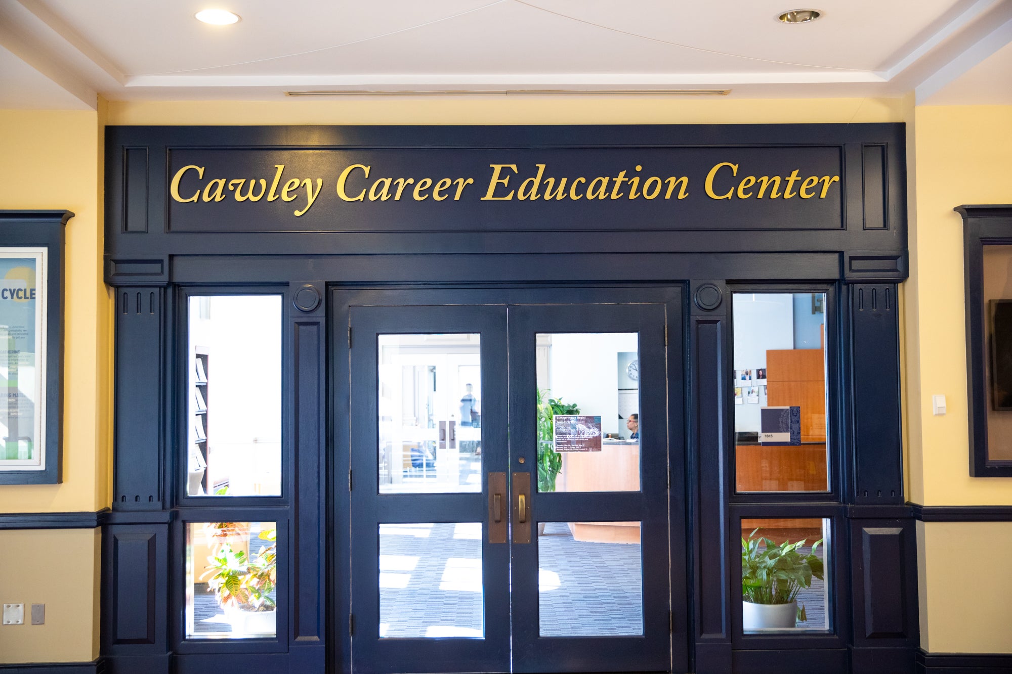 The words "Cawley Career Education Center" are engrained in gold letters above a set of glass doors with navy blue frames.