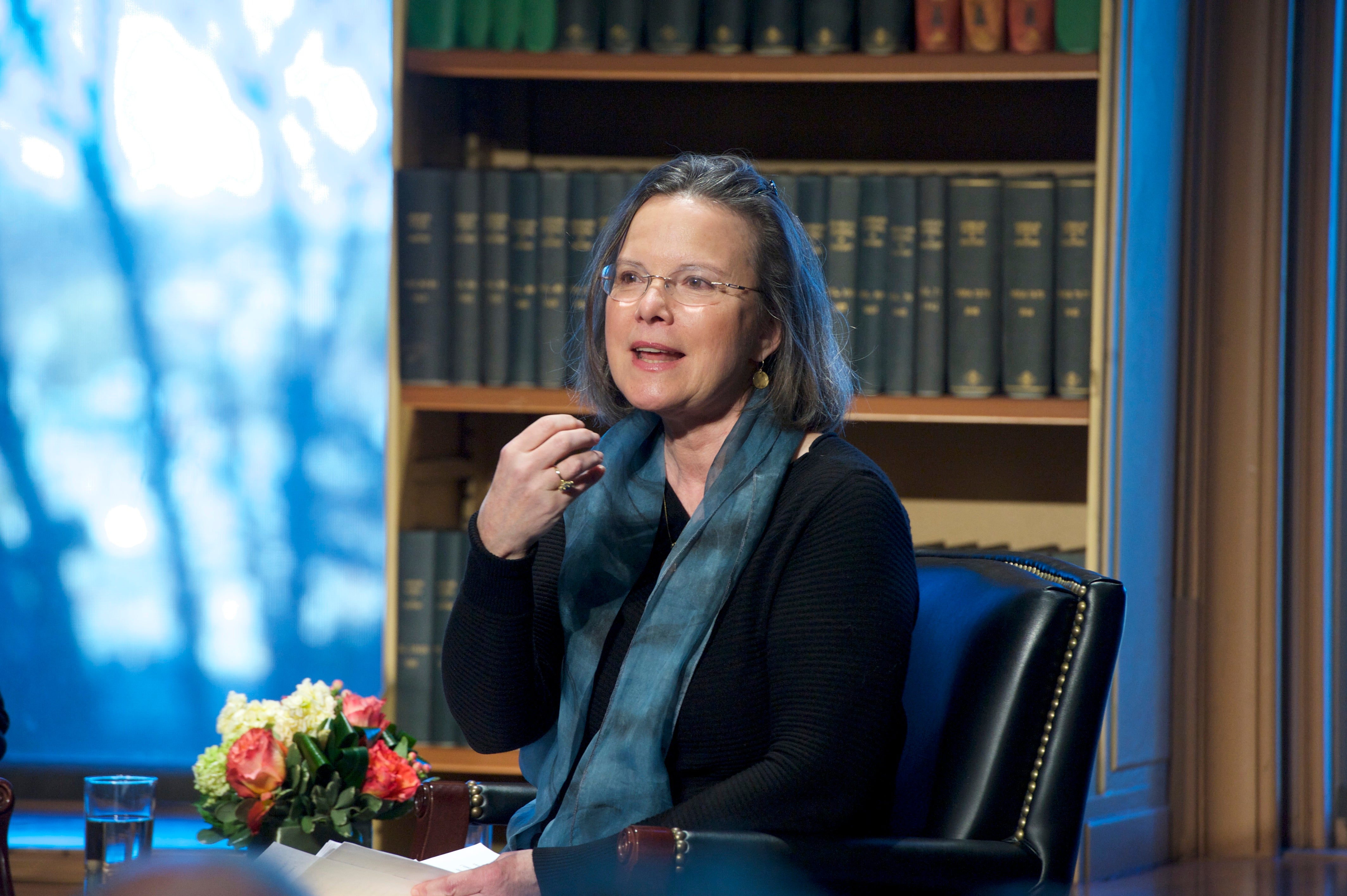 Carolyn Forché sits in a library with books behind her