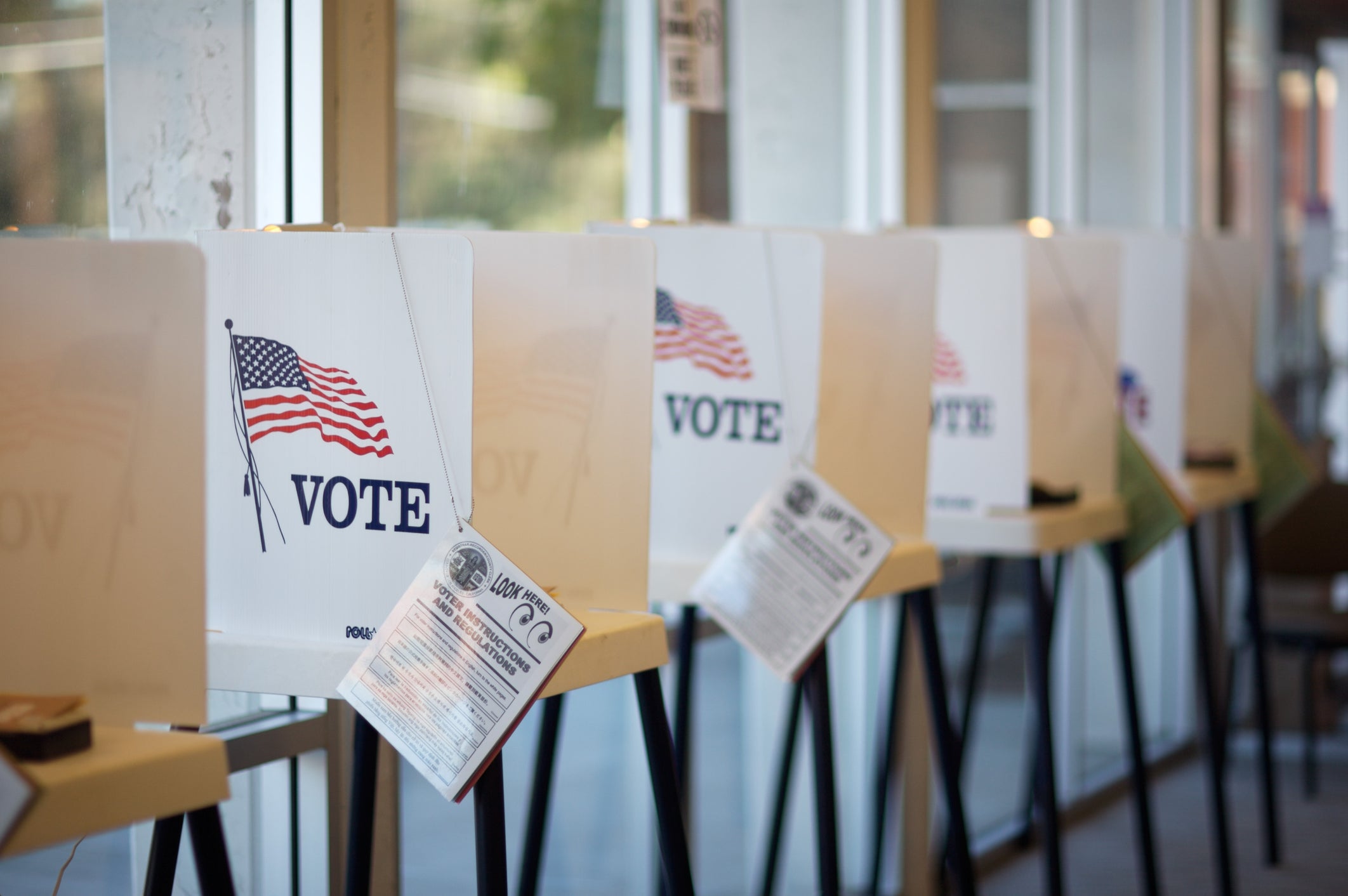 Voting booths lined up with the word "vote" and an American flag on them and a ballot information attached