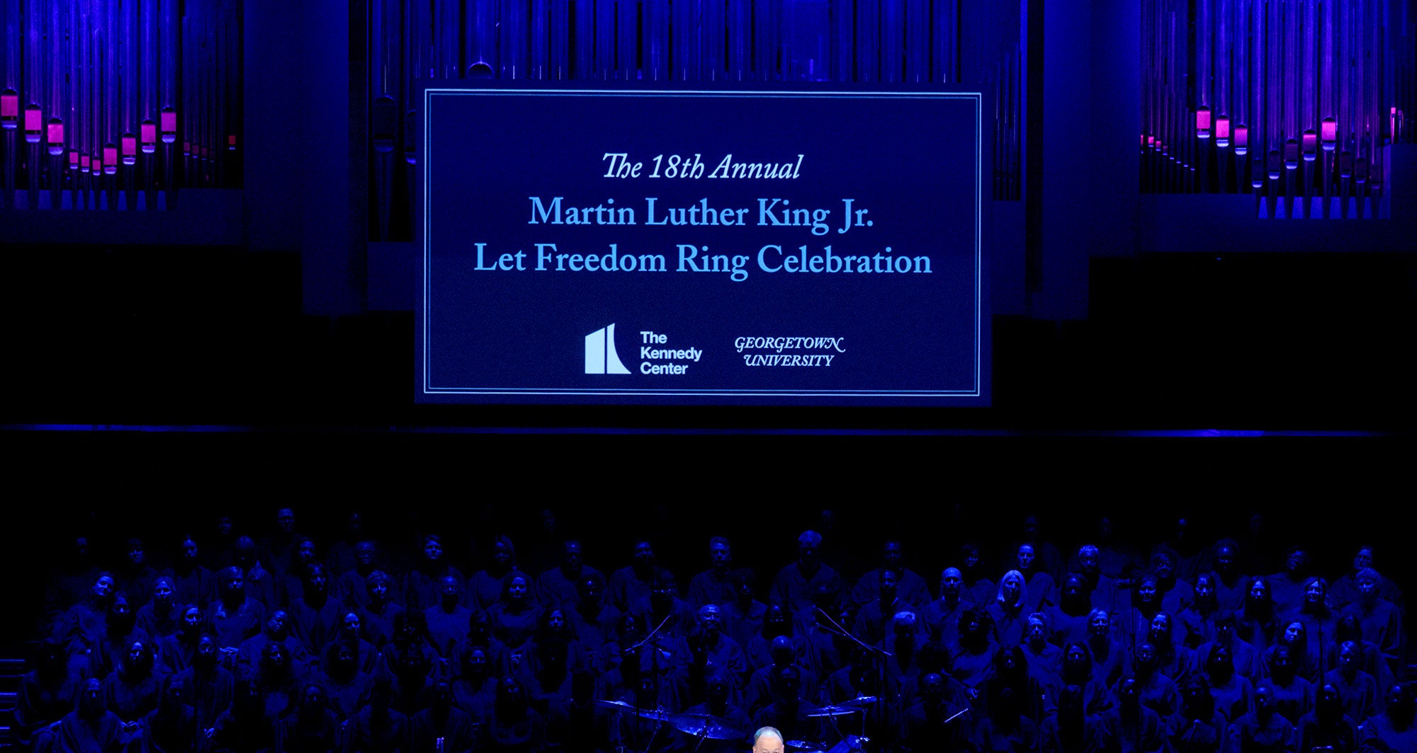 A "Martin Luther King Jr., Let Freedom Ring" banner hangs on a darkly lit stage.