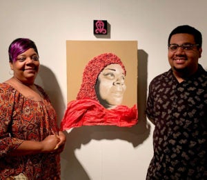 Kenlontaé Turner and Shameka Fallin stand near a piece of artwork hanging on the wall.