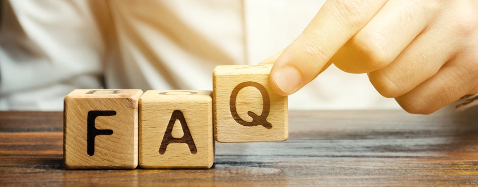 Person puts wooden blocks with the word FAQ (frequently asked questions).