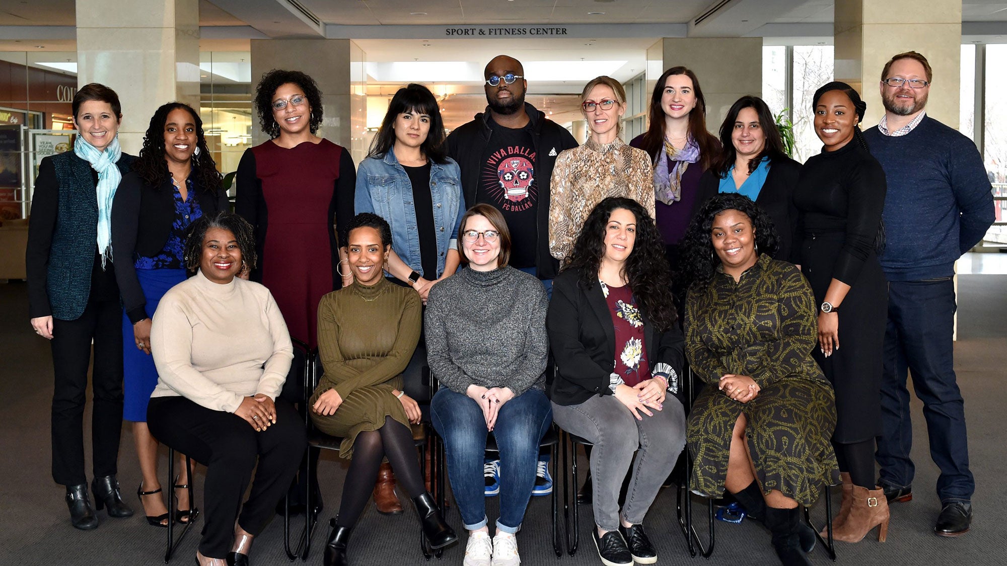 A group of 15 juvenile justice defenders and professors sit and stand for a photo indoors.