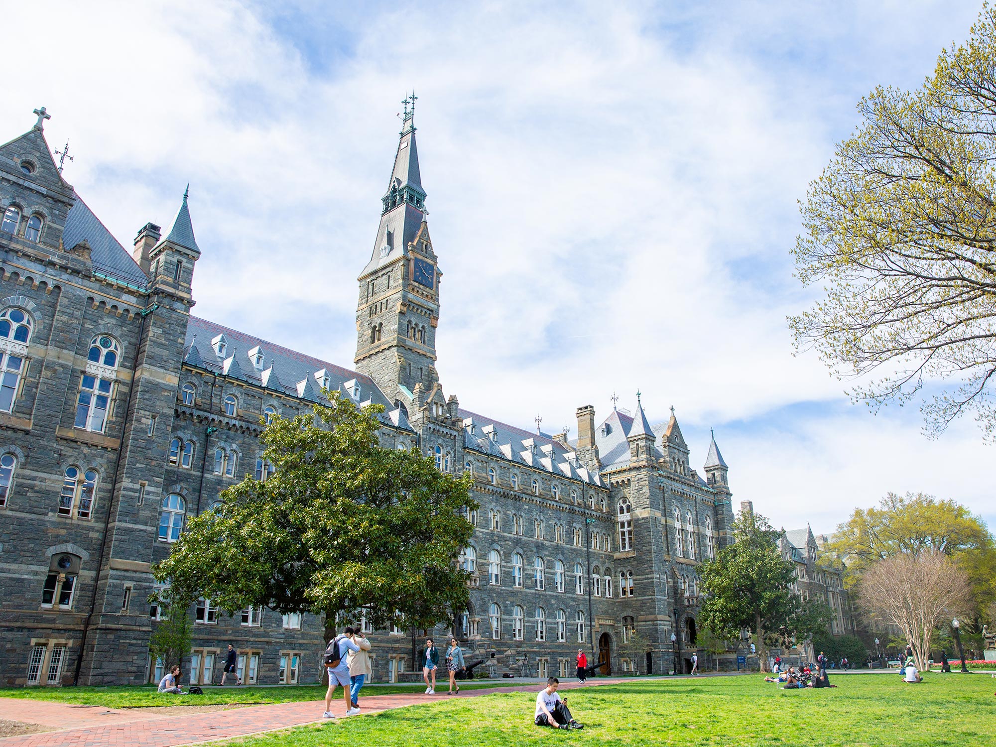 View of Healy Hall from the left of the building on a spring day with white clouds covering most of a blue sky