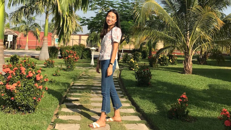 Dayhe Yoon in Ghana on a path outside with tropical plants on either side