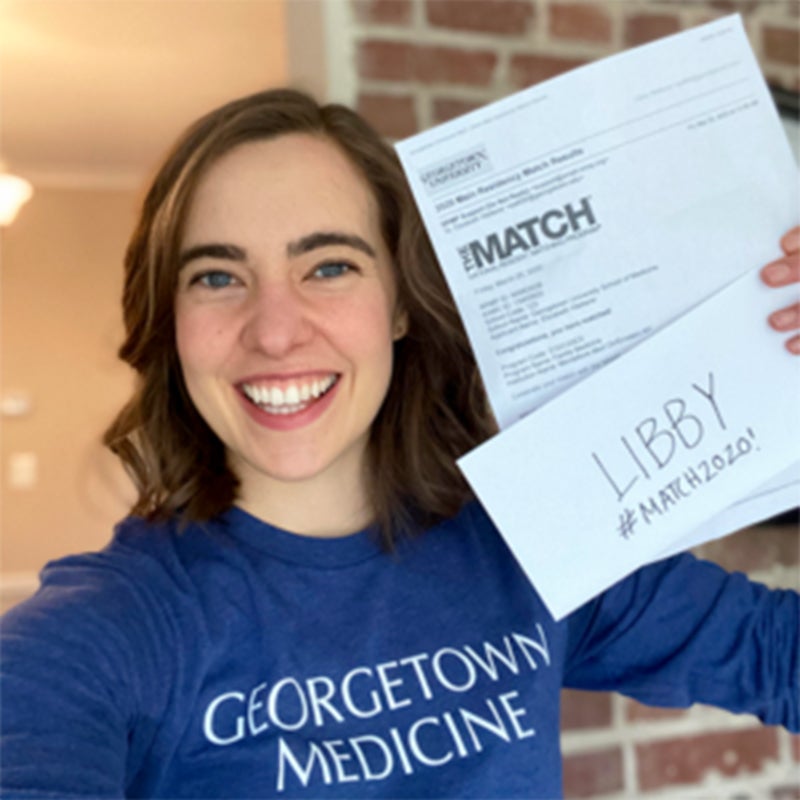 Elizabeth Wetter wearing a Georgetown Medicine shirt shows off her envelope and letter telling her where she'll do her residency