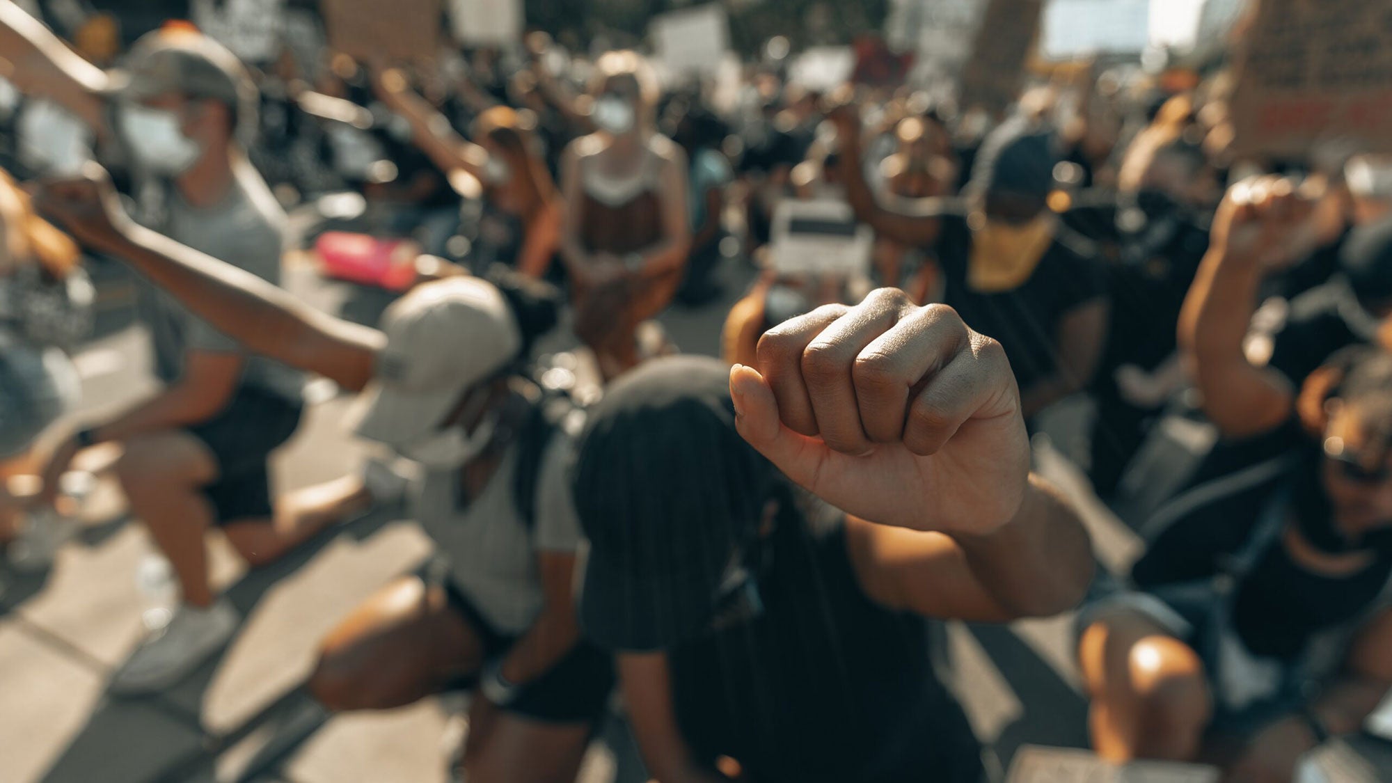 a crowd of people kneel with their fists in the air.