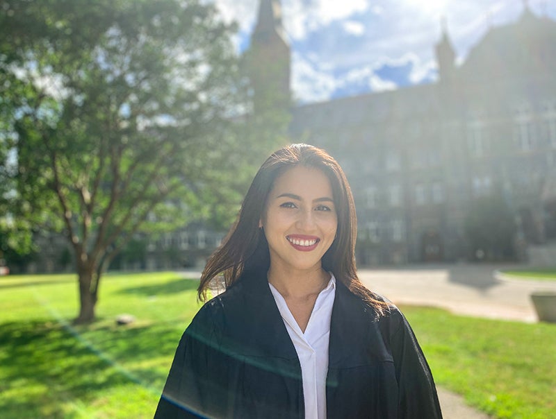 Elinor Walker wearing an academic robe in from of the Healy Building.