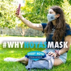 A student takes a selfie with a mask on with text that says "#WhyHoyasMask"