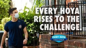 A student puts on a mask with the text "Every Hoya Rises to the Challenge."