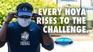 A student puts on a mask with the text "Every Hoya Rises to the Challenge."