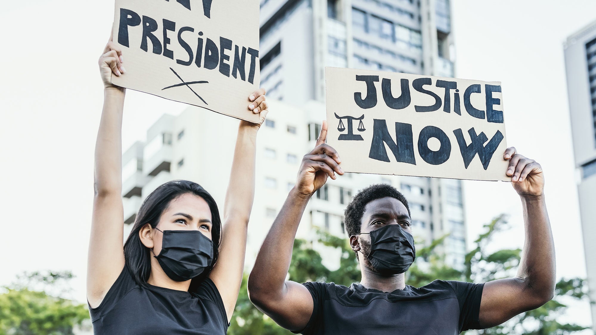 Two demonstrators hold up signs that read "President" and "Justice Now."