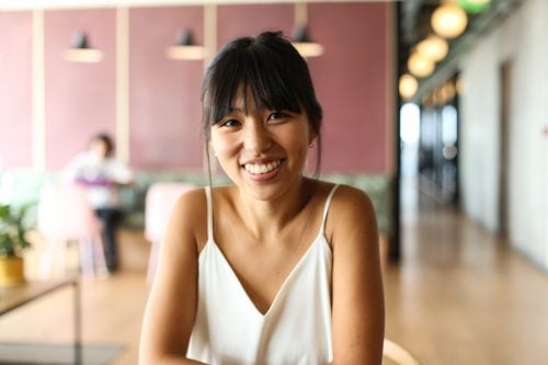 Lucia wears a white shirt in front of a coworking space