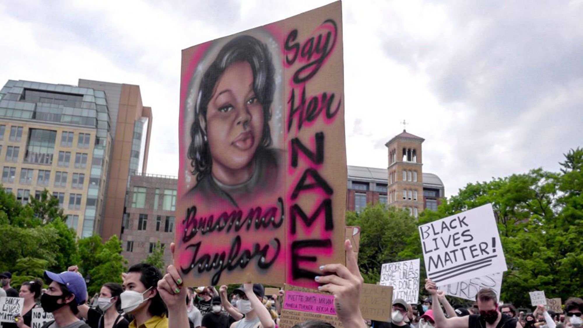 People stand in front of a mural of Breonna Taylor.