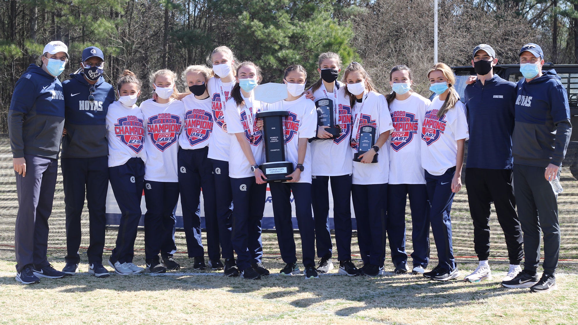 The women's cross country team and coaches pose with the BIG EAST Championship trophy.