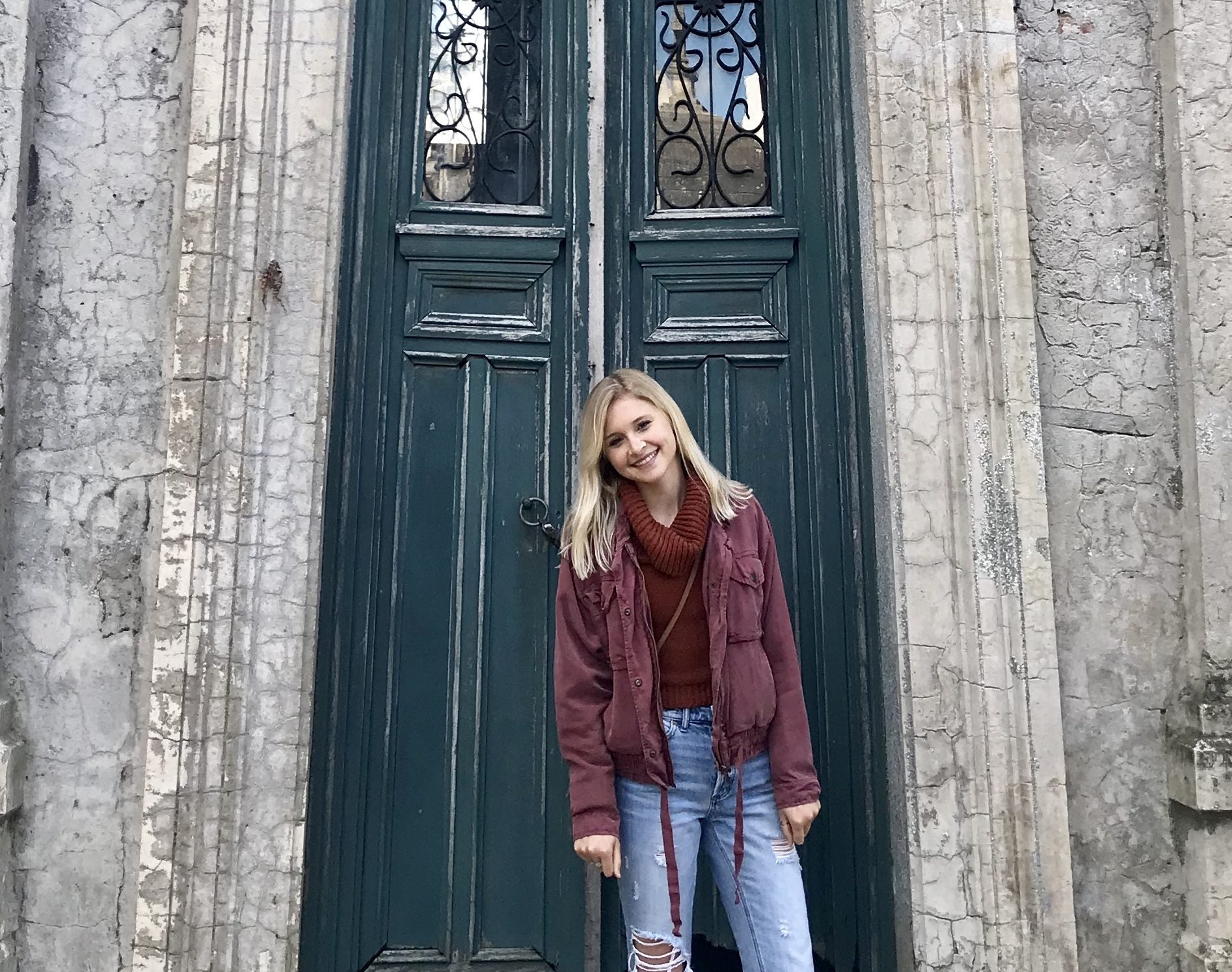 Grace Keegan stands in front of an old door on a stone building