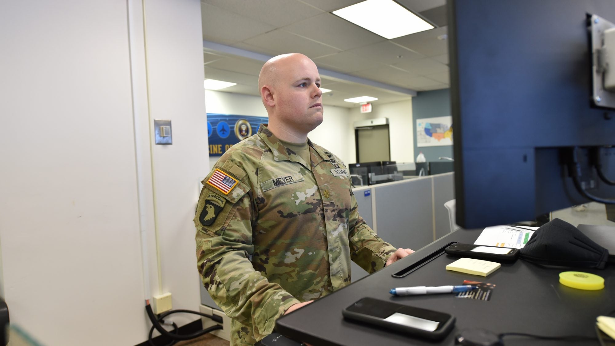 Doug Meyer wears army uniform while standing in front of a computer