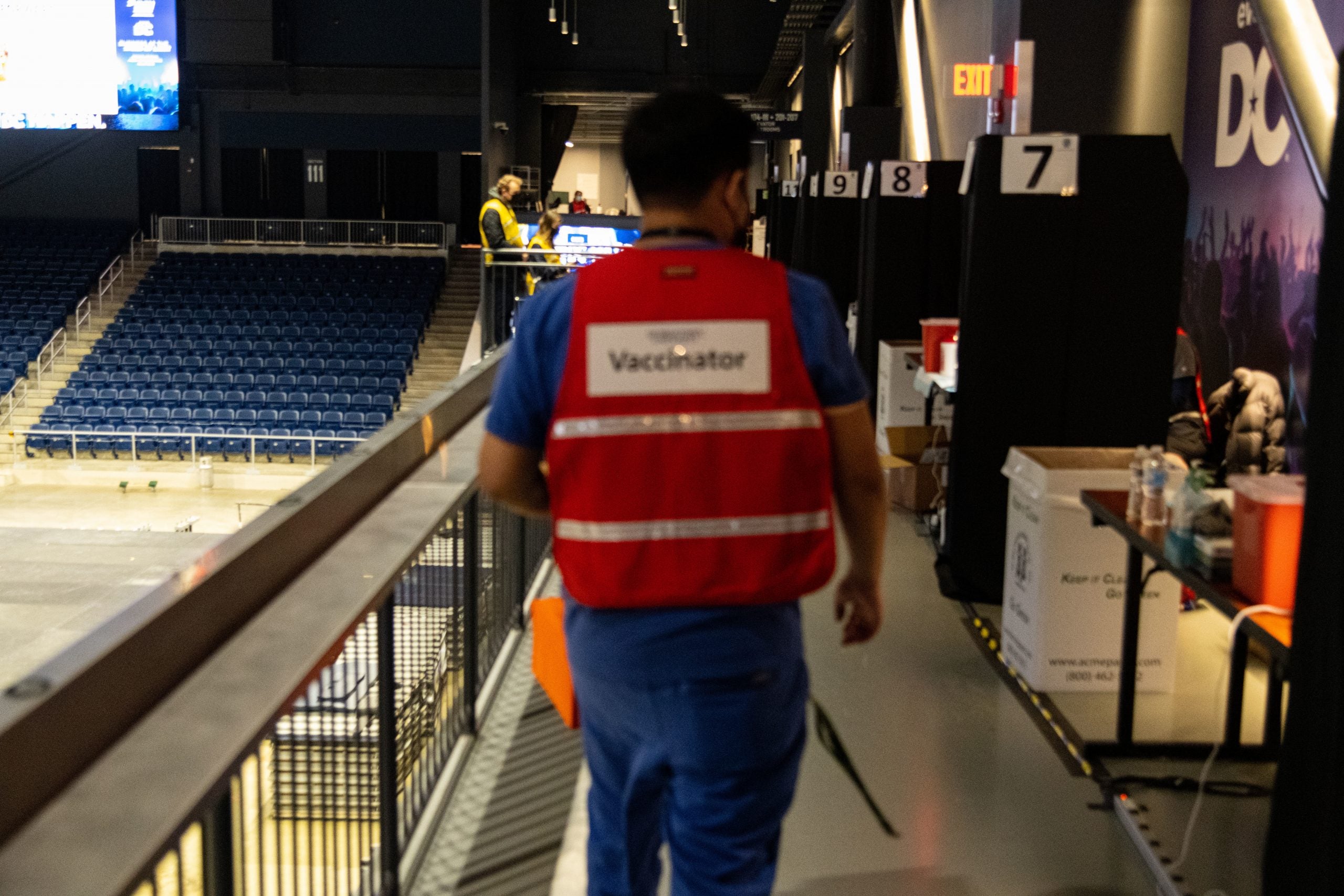 Vaccinator wearing a red vest walking