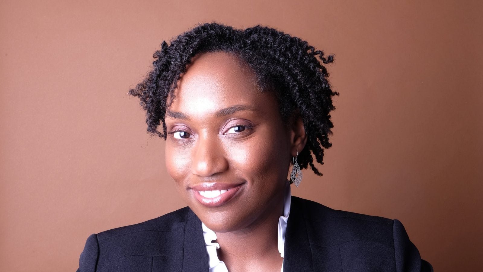 Marcia Chatelain wears a blazer in front of a brown background