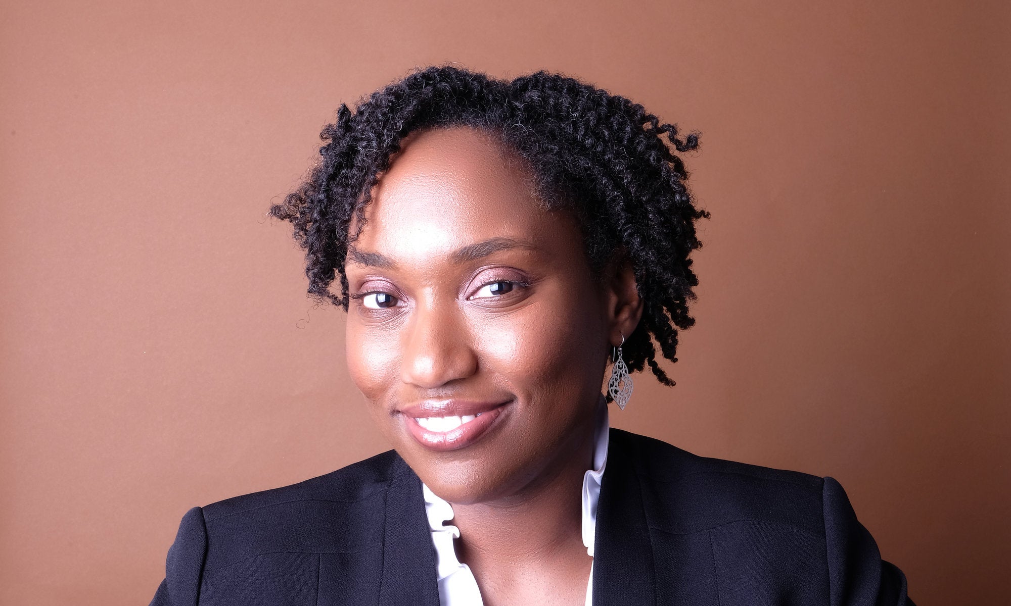 Marcia Chatelain wears a blazer in front of a brown background