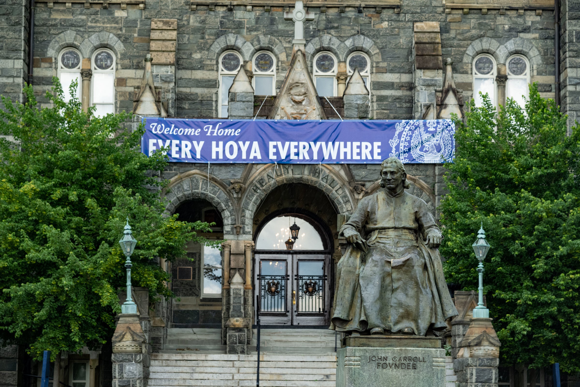 John Carroll statue in front of Healy Hall with the sign "Welcome Home Every Hoya Everywhere"