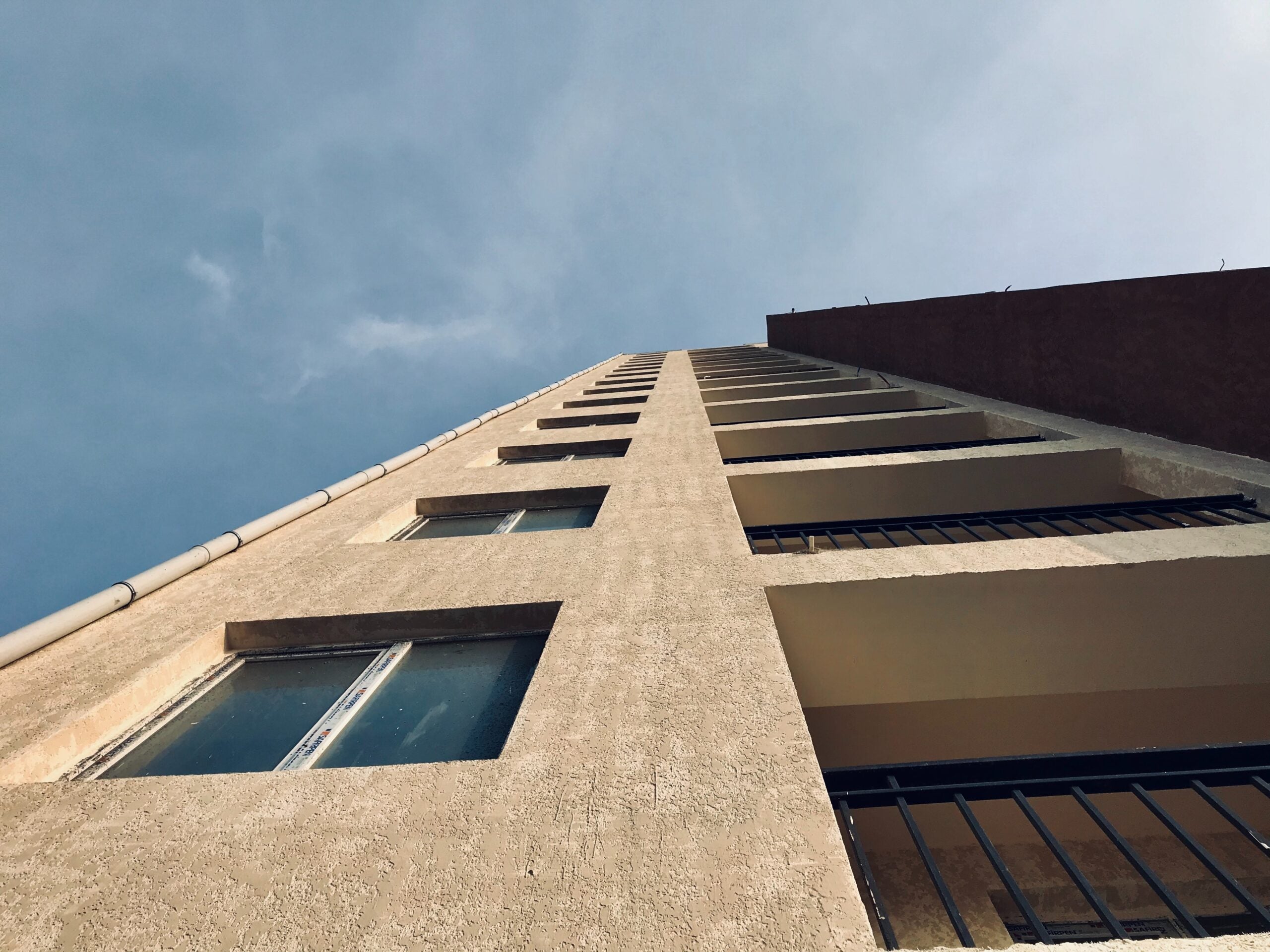 Side of a cement building looking up toward a blue-gray sky