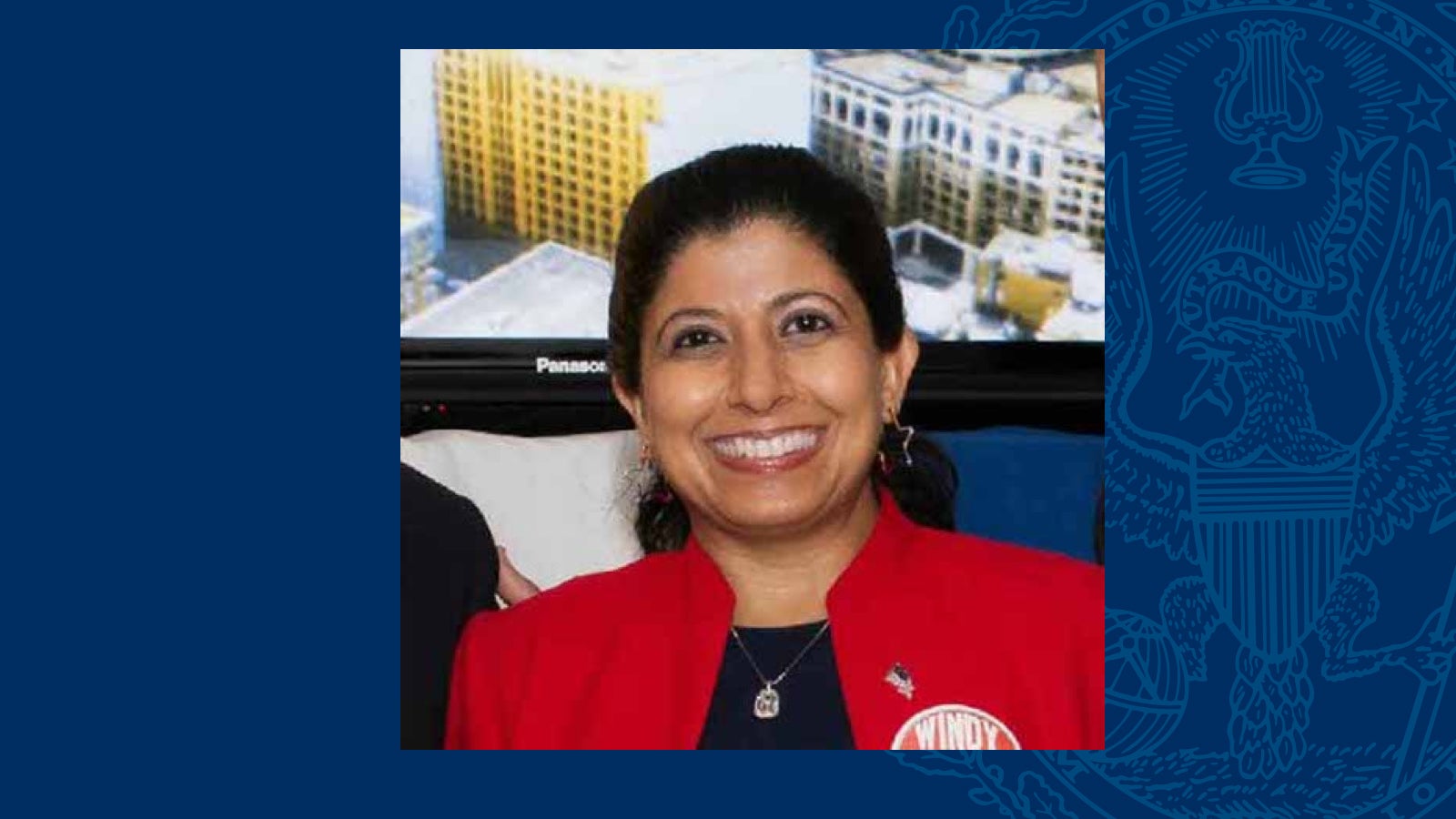 Nazima Razick wears a red blazer in a square headshot on a blue background